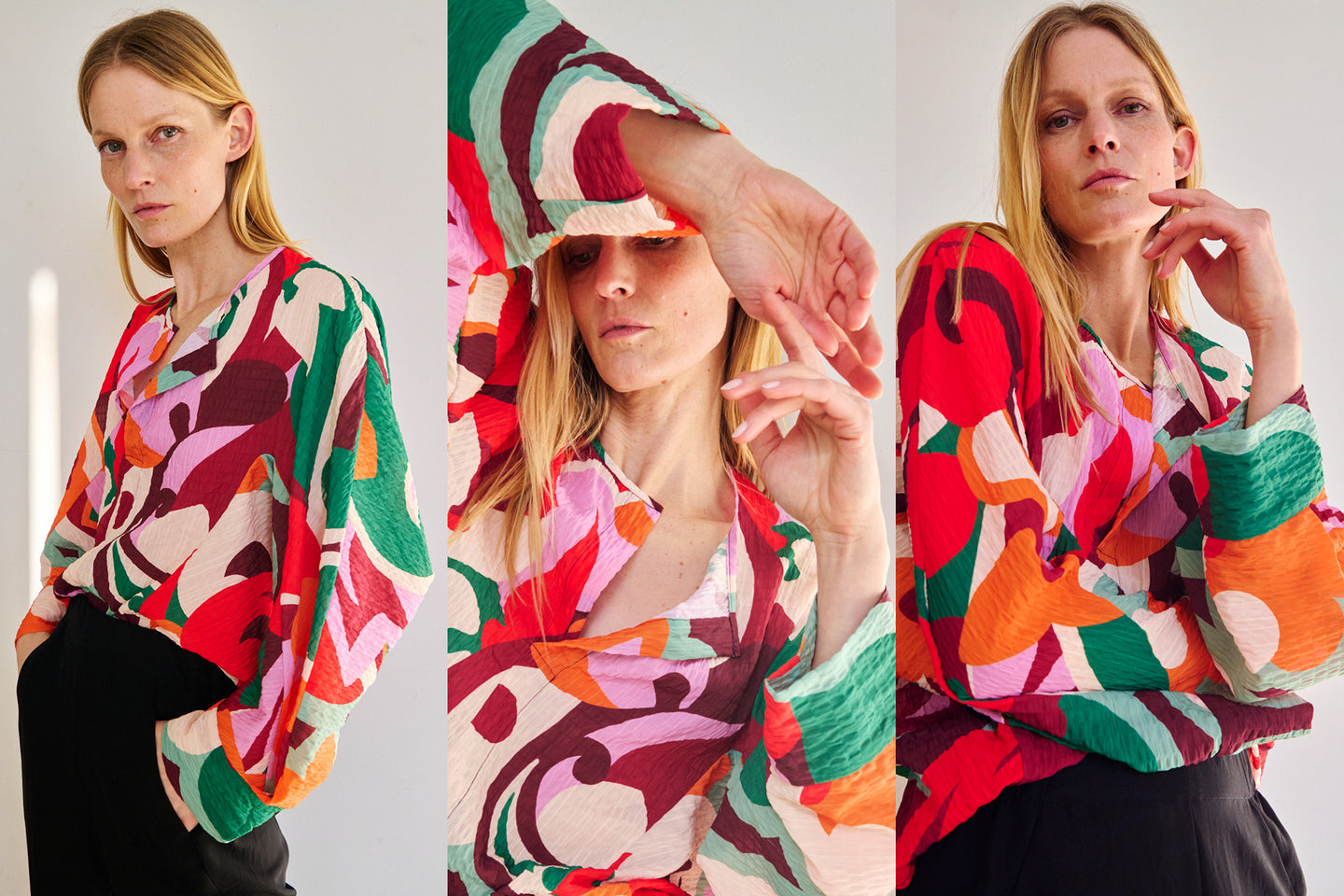 A woman with long blond hair poses in three different positions, wearing a colorful abstract patterned blouse and black pants, stands against a plain background with a neutral expression. The Long-Sleeved Akeo Shirt in Pop Paisley Print by Zero + Maria Cornejo features vibrant reds, greens, pinks, and oranges.