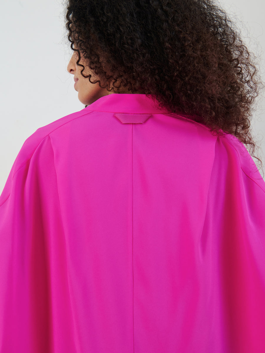 A person with curly hair is seen from the back, wearing the vibrant Long-Sleeved Fin Gaban Shirt in silk charmeuse by Zero + Maria Cornejo. The shirt features a collar and drapes loosely over the shoulders against a neutral background.