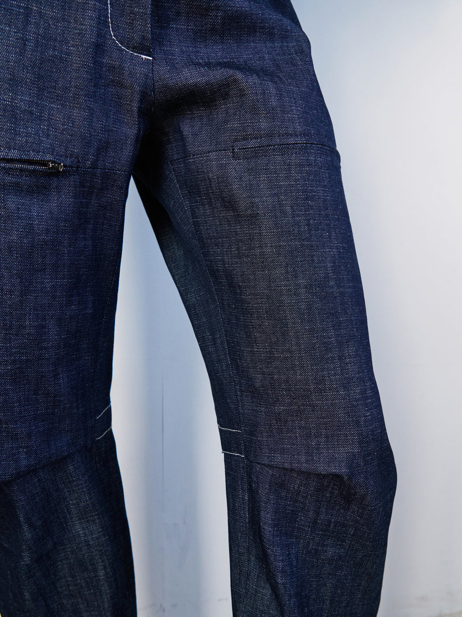 Close-up of Denim Biker Pant by Zero + Maria Cornejo, featuring organic denim with a dark blue hue, subtle fades, and prominent white stitching around the pockets and seams.