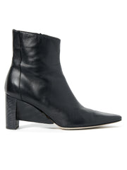 The Lia Boot by Zero + Maria Cornejo is a black smooth nappa leather ankle boot featuring a pointed toe and a distinctive sculptural wedge heel that curves slightly towards the back. The leather is smooth and slightly glossy, complemented by a convenient side zipper. Made in Italy.