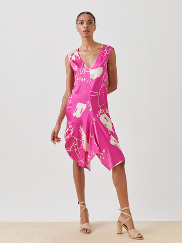 Wearing the Aura Dress - Final Sale by Zero + Maria Cornejo, a bright pink sleeveless knee-length dress with abstract white patterns from sustainable screen-printing, paired with beige strappy heels against a plain white background.