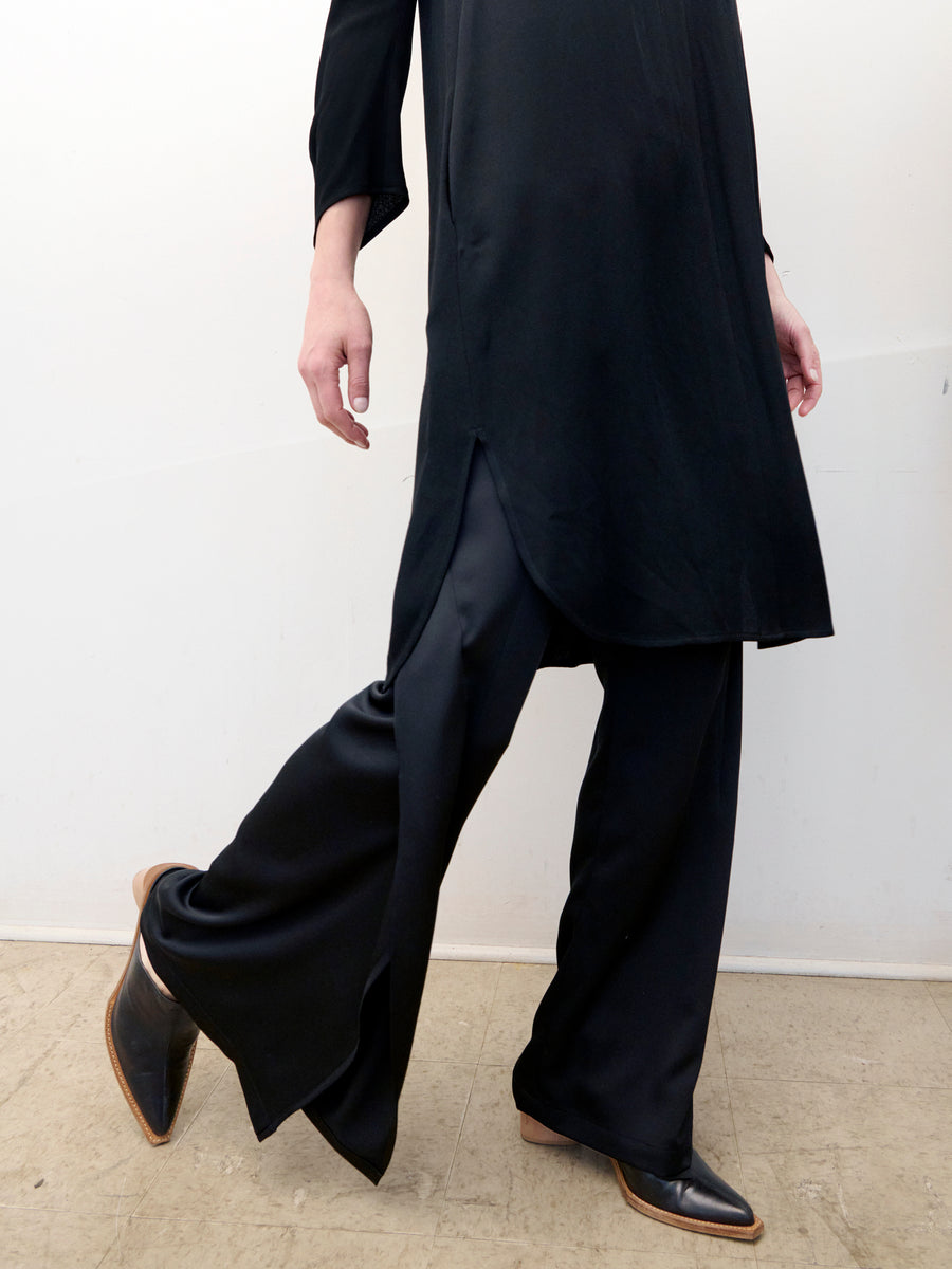 A person wearing a long black tunic with side slits and the 