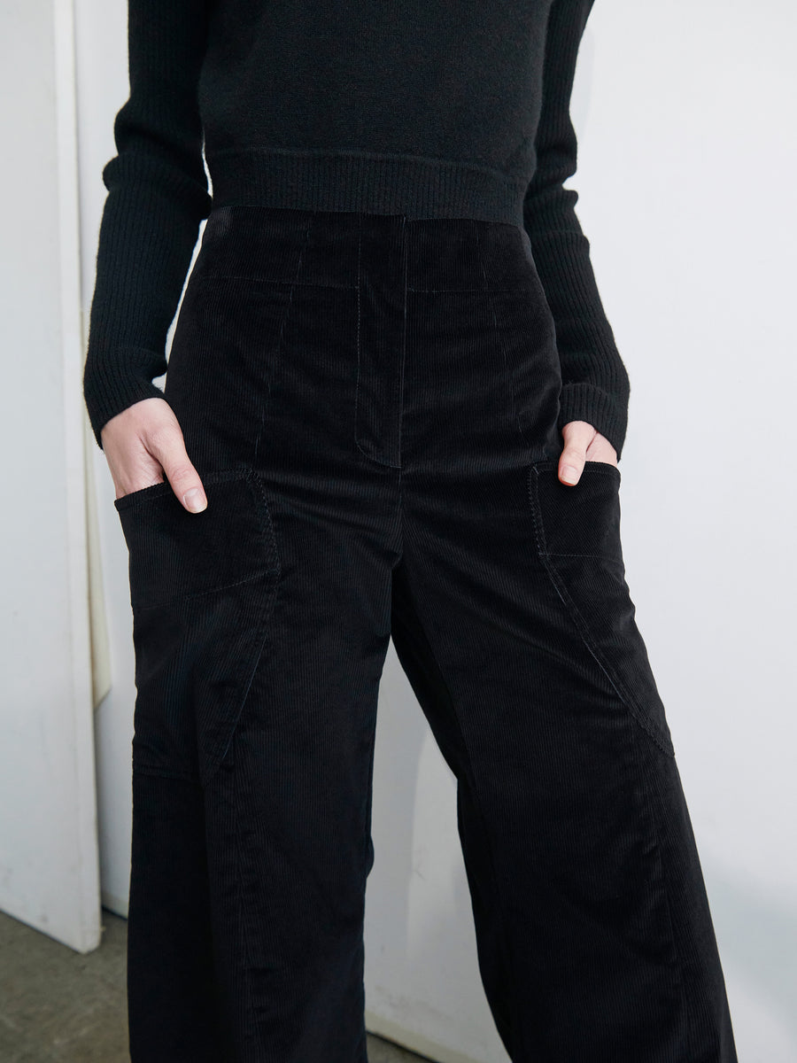 Person in a black, long-sleeved top and the Curved Eda Culotte from Zero + Maria Cornejo, standing against a neutral background. Both hands rest in their front patch pockets. The outfit appears stylish and minimalistic.