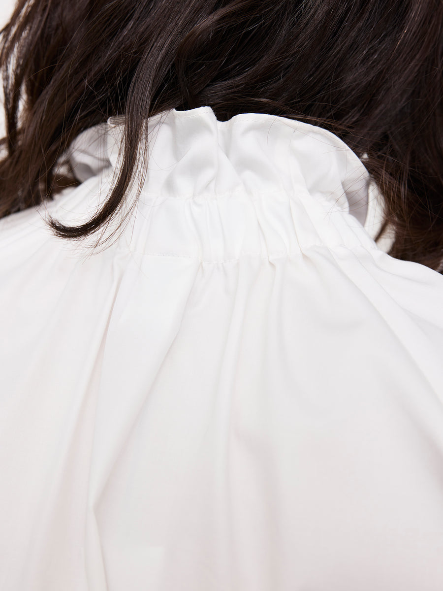 Close-up of the back of a person wearing the Elastic Gaban Shirt by Zero + Maria Cornejo. The white ruffle collar, crafted in New York, is partially covered by the person's dark hair.
