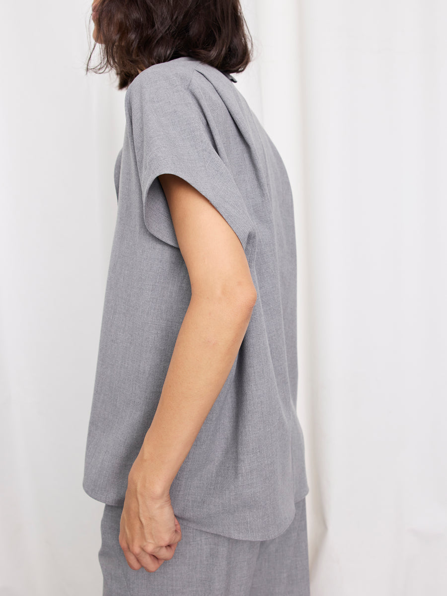 A person with shoulder-length dark hair models the loose-fitting Fin Gaban Shirt by Zero + Maria Cornejo, paired with matching pants, standing sideways against a plain white background.
