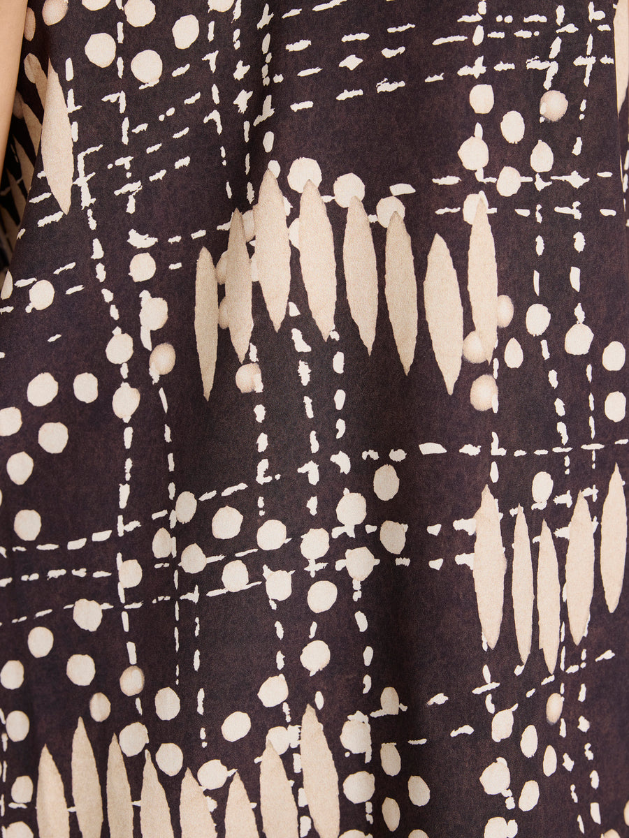 Close-up of the Ony Tank by Zero + Maria Cornejo, crafted in silk charmeuse with a batik-inspired print of cream dots, dashes, and ovals on a dark brown background.
