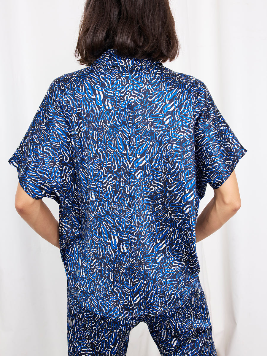 A person with shoulder-length dark hair faces away, wearing the Circle Shirt by Zero + Maria Cornejo with matching pants against a white background.