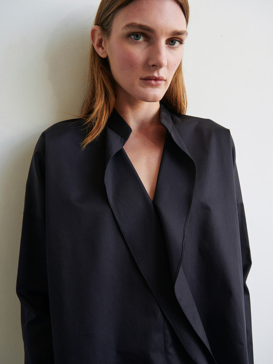 A person with shoulder-length brown hair is wearing a loose-fitting, long-sleeved Fin Gaban Shirt by Zero + Maria Cornejo. They are standing against a plain white background and looking directly at the camera with a neutral expression.