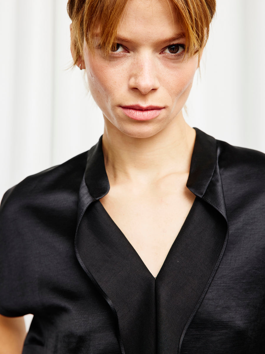 A person with light skin and light brown hair wears the Zero + Maria Cornejo Fin Gaban Shirt, featuring a black stand collar, and looks directly at the camera with a neutral expression against a light background.