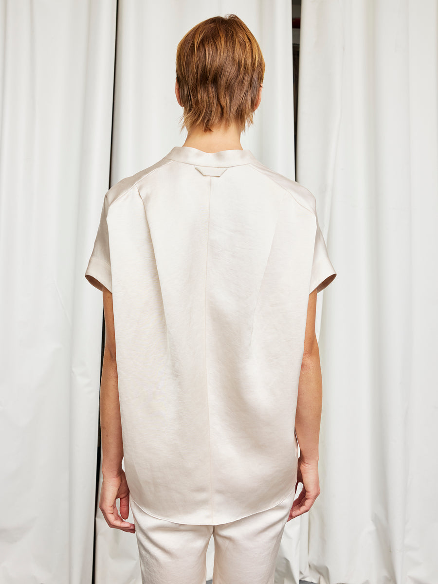 A person with short light brown hair stands with their back to the camera, wearing the Zero + Maria Cornejo Fin Gaban Shirt and matching pants in front of white curtains.