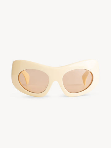 The Port Tanger Ruh sunglasses by Port Tanger feature a cream oval oversize mask frame and light brown tinted lenses with 100% UVA/UVB protection, shown on a plain white background.