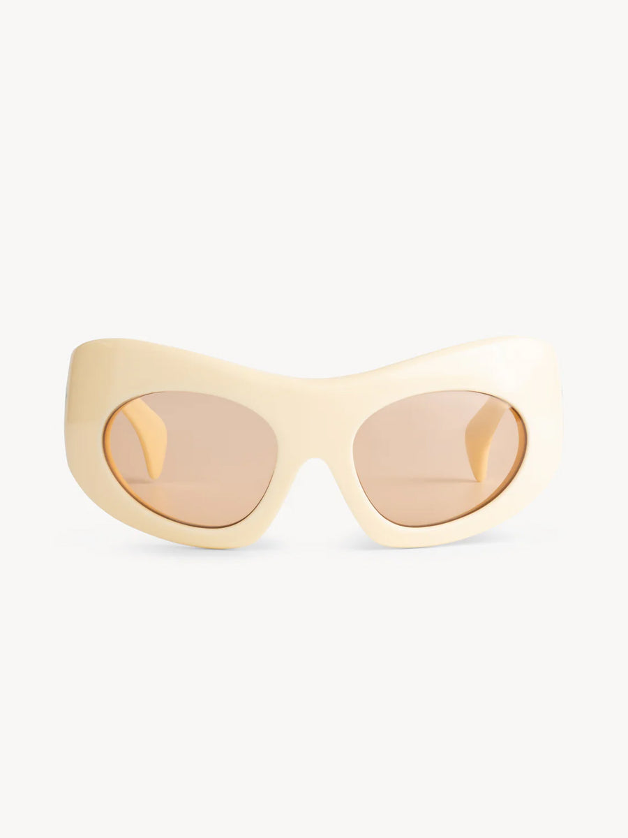 The Port Tanger Ruh sunglasses by Port Tanger feature a cream oval oversize mask frame and light brown tinted lenses with 100% UVA/UVB protection, shown on a plain white background.