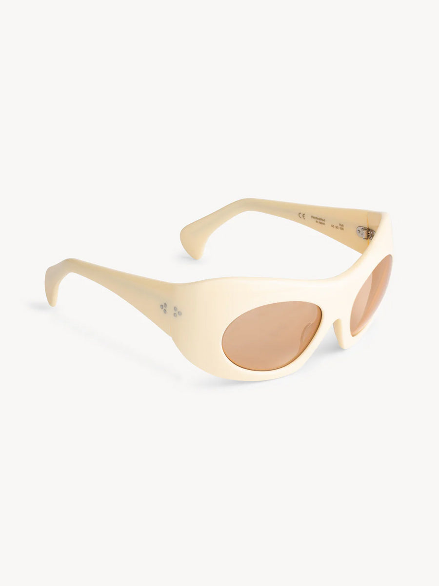 Port Tanger Ruh sunglasses by Port Tanger feature a cream-colored, oval-shaped oversize mask frame handcrafted in Japan with light brown tinted lenses offering 100% UVA/UVB protection, shown on a white background.
