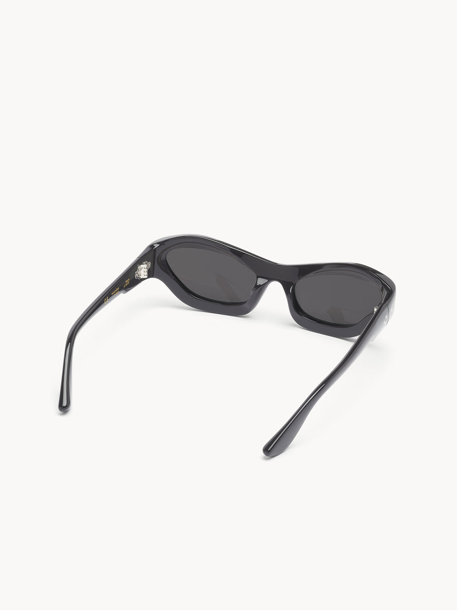 The Port Tanger Hayya by Port Tanger are black, oval-shaped unisex sunglasses with dark lenses providing UVA/UVB protection. Shown on a white background, the sunglasses have open arms and lenses facing away.