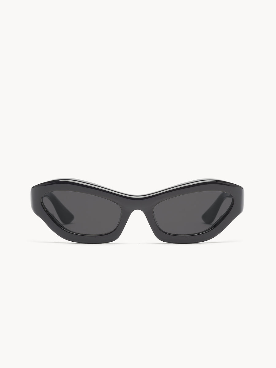 Port Tanger Hayya by Port Tanger: sleek black cat-eye sunglasses with dark tinted lenses offer UVA/UVB protection. Modern, sharp-edged unisex eyewear displayed on a plain white background.