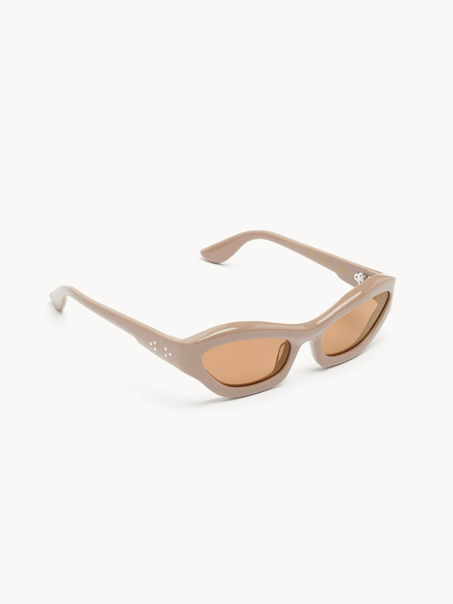 The Port Tanger Hayya by Port Tanger features beige cat-eye sunglasses with thick frames, brown-tinted lenses, unisex style, and UVA/UVB protection, shown on a white background.