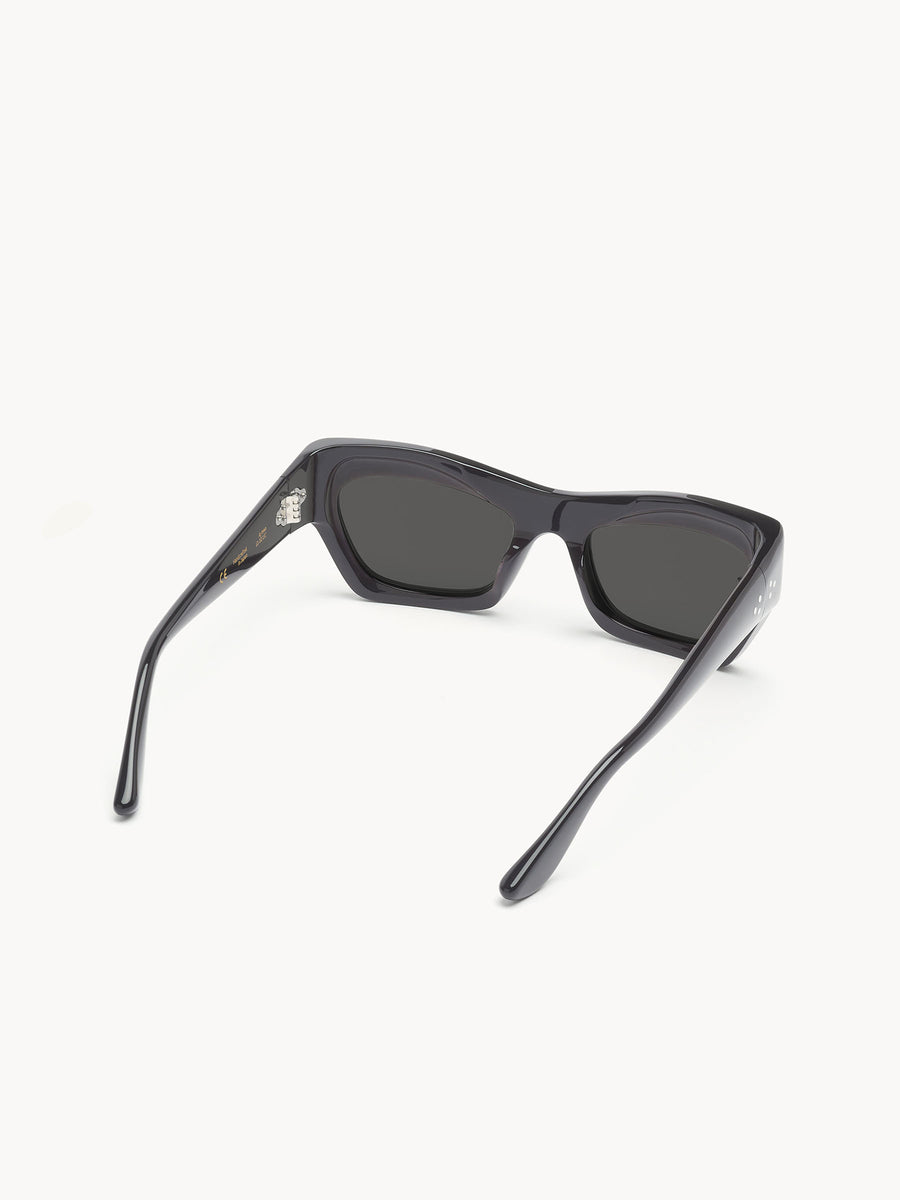 Port Tanger Ayreen by Port Tanger: black rectangular sunglasses with dark lenses, shown from the back on a white background. Arms are partially open and angled outward, providing 100% UVA/UVB protection.