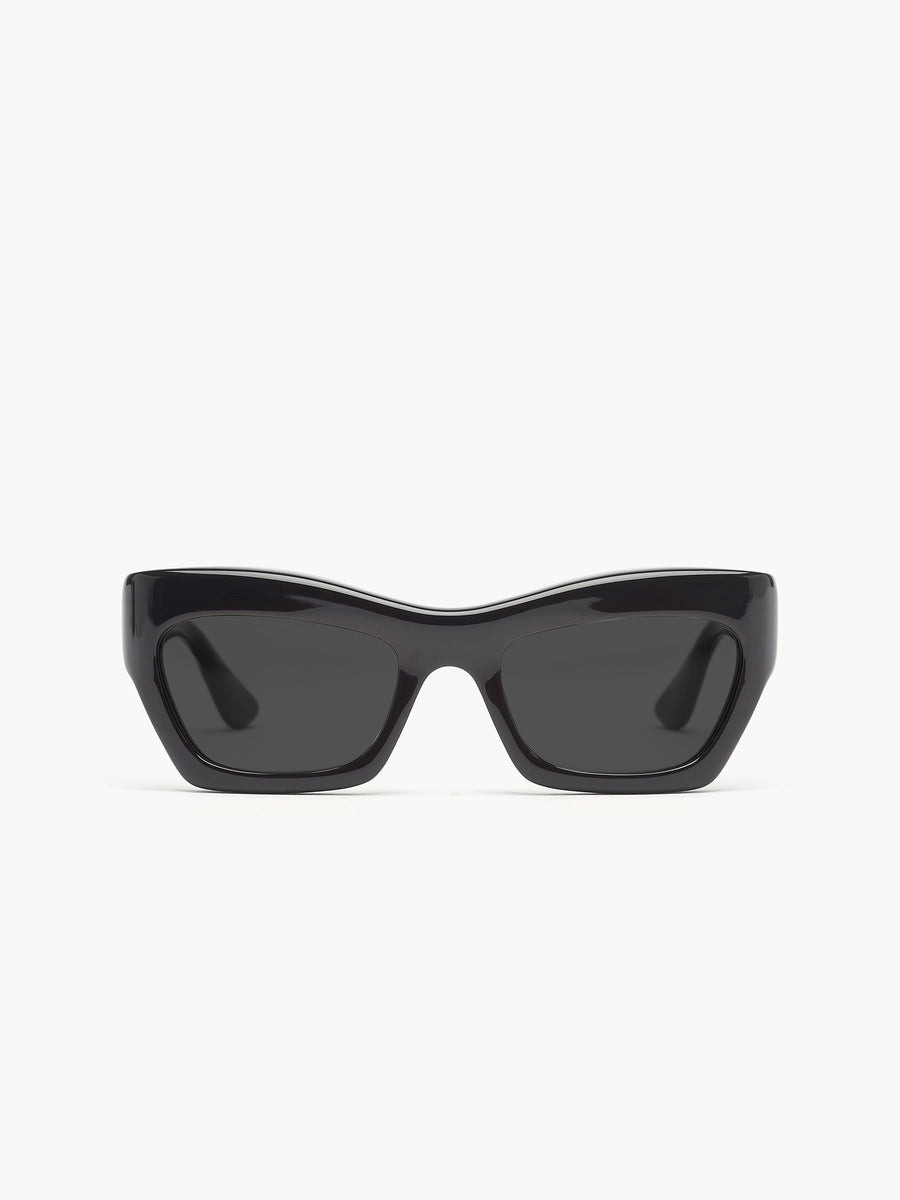 The Port Tanger Ayreen by Port Tanger are black rectangular sunglasses with thick, glossy frames and dark lenses, handcrafted in Japan and shown against a plain white background.