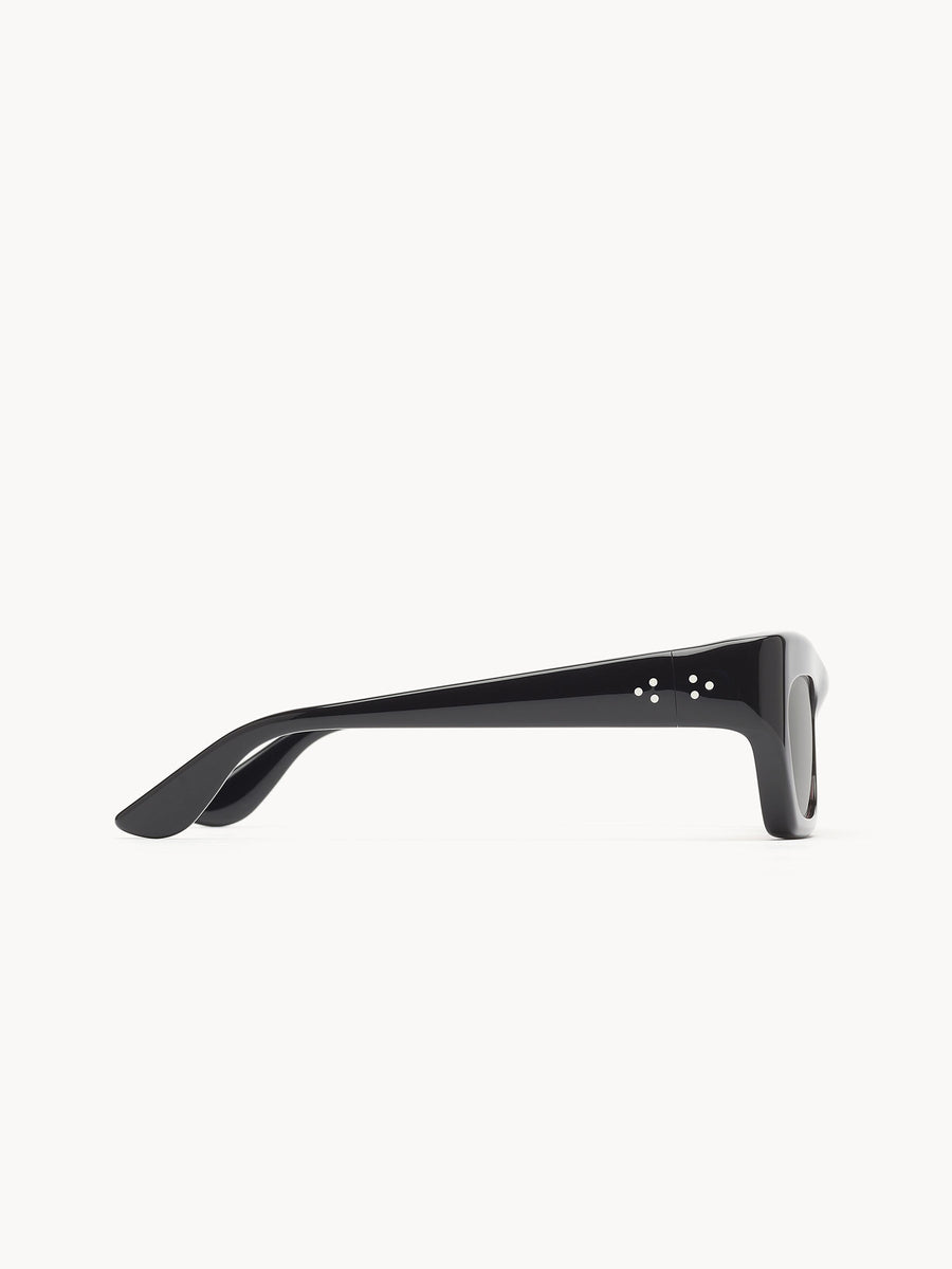 Side view of Port Tanger Ayreen black rectangular sunglasses with thick frames and small silver dots by the hinge, handcrafted in Japan by Port Tanger, shown on a white background.