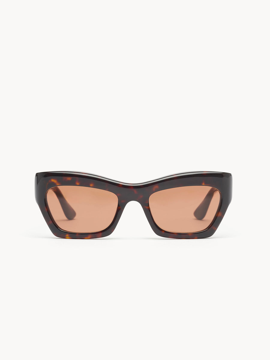 The Port Tanger Ayreen sunglasses by Port Tanger feature thick, angular cat-eye tortoiseshell frames with brown-tinted rectangular lenses, handcrafted in Japan with 100% UVA/UVB protection. Displayed on a plain white background.