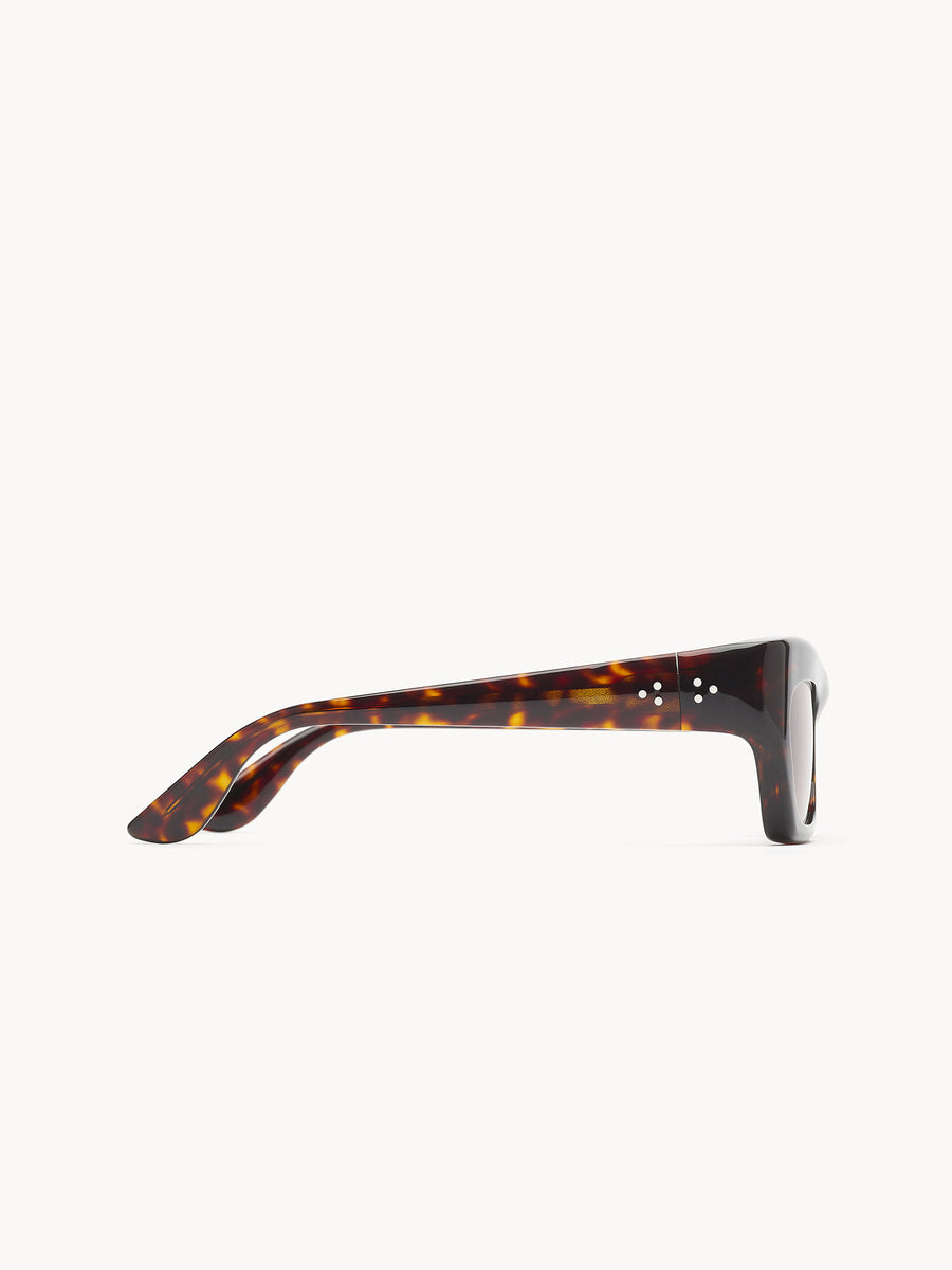 Side view of Port Tanger Ayreen sunglasses by Port Tanger featuring a tortoiseshell cat-eye frame, thick arms, and dark lenses, handcrafted in Japan and displayed against a plain white background.
