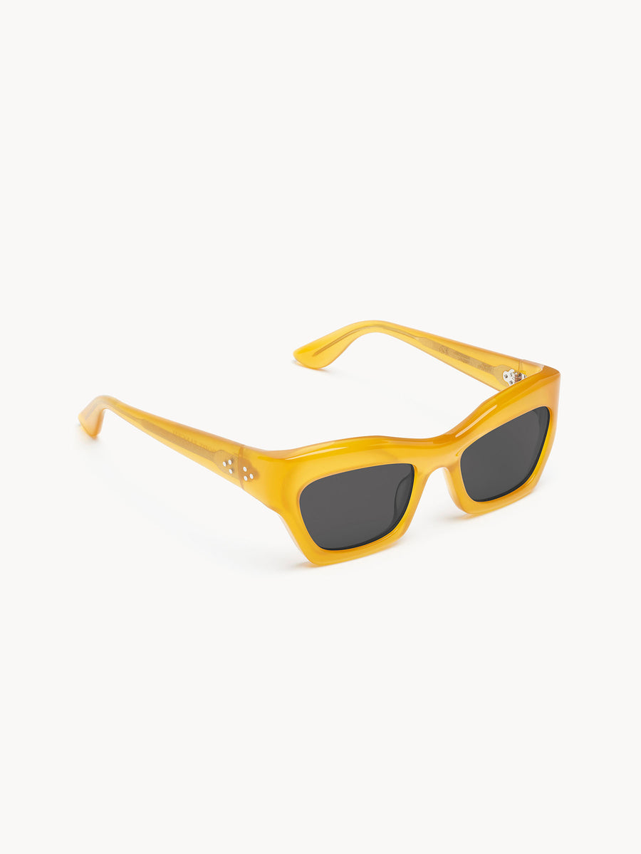 Port Tanger Ayreen by Port Tanger: yellow rectangular sunglasses with thick, glossy frames and black lenses. Silver details accent the hinges. Provides 100% UVA/UVB protection. Shown on a white background.