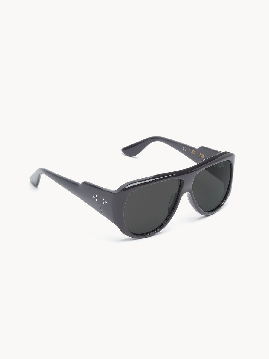 Port Tanger Gambia sunglasses by Port Tanger, shown on a white background, feature black rectangular glossy frames with subtle silver dots by the hinges and dark lenses that provide UVA/UVB protection.