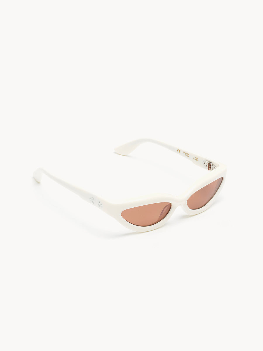 Port Tanger Fanna by Port Tanger: White cat-eye sunglasses handcrafted in Japan with pink-tinted lenses, providing 100% UVA/UVB protection. Displayed on a plain white background.