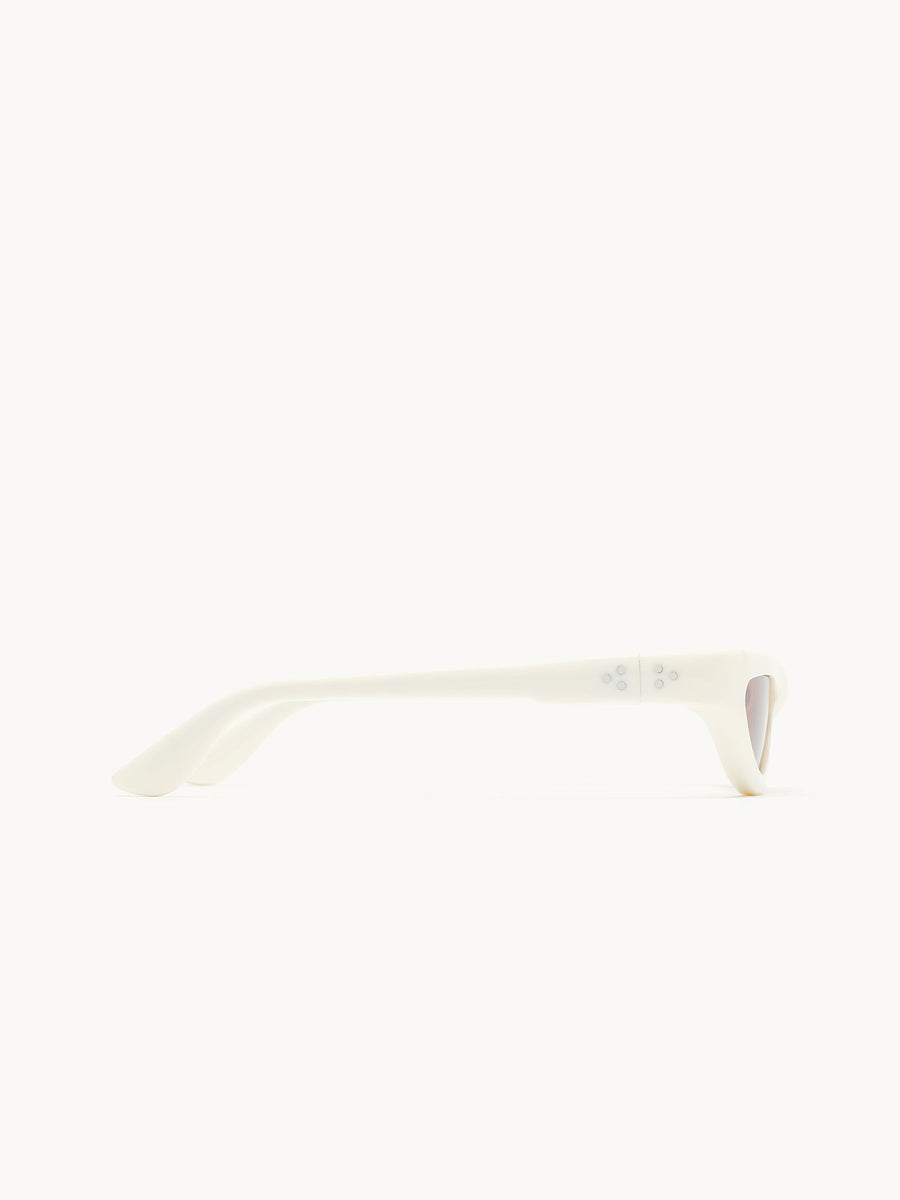 Side view of Port Tanger Fanna white cat-eye sunglasses with thick arms, showing one arm and the lens edge against a plain white background.