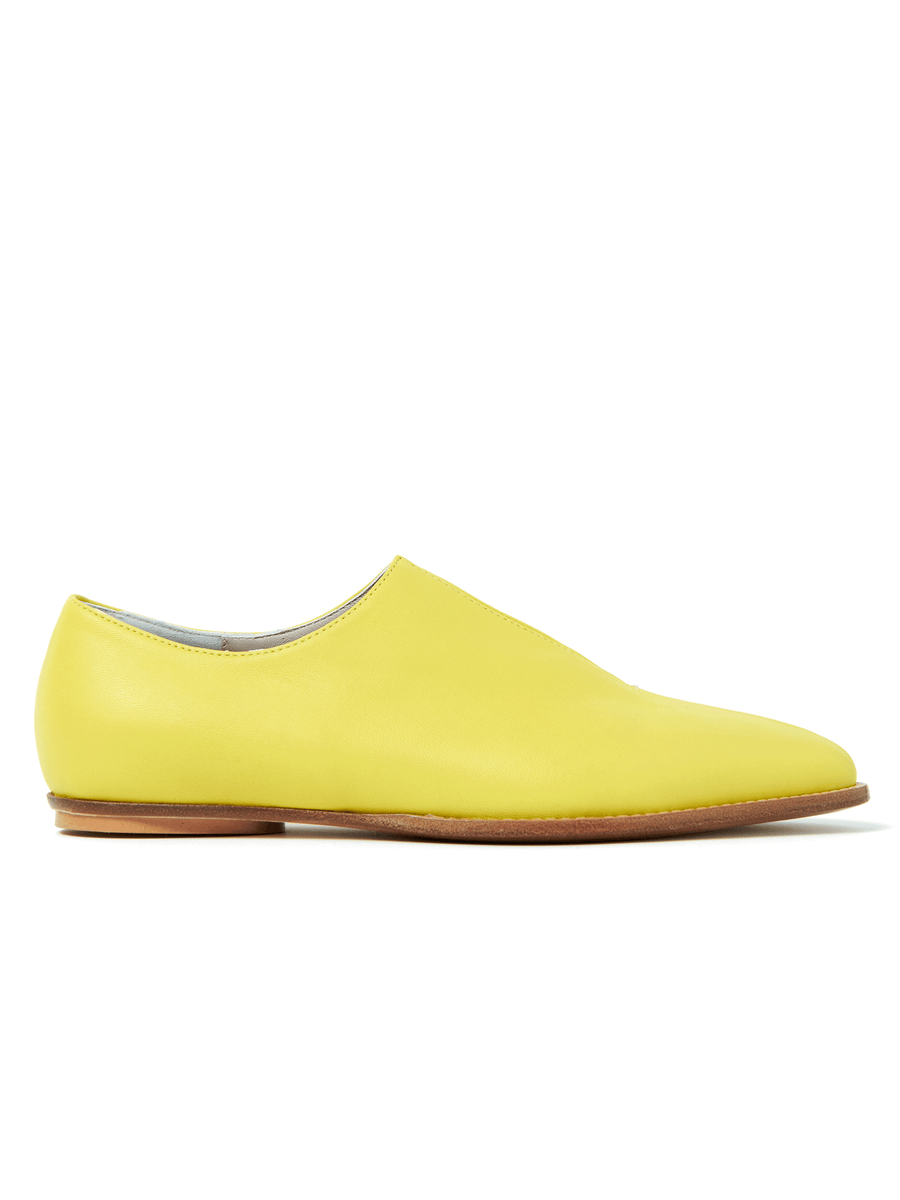 The Kiara Oxford by Zero + Maria Cornejo is a yellow Nappa leather flat shoe with a minimalist design, featuring a rounded toe and brown sole. Crafted in Italian sizing, it offers a seamless, smooth look without visible laces or embellishments. Note: this item is final sale.