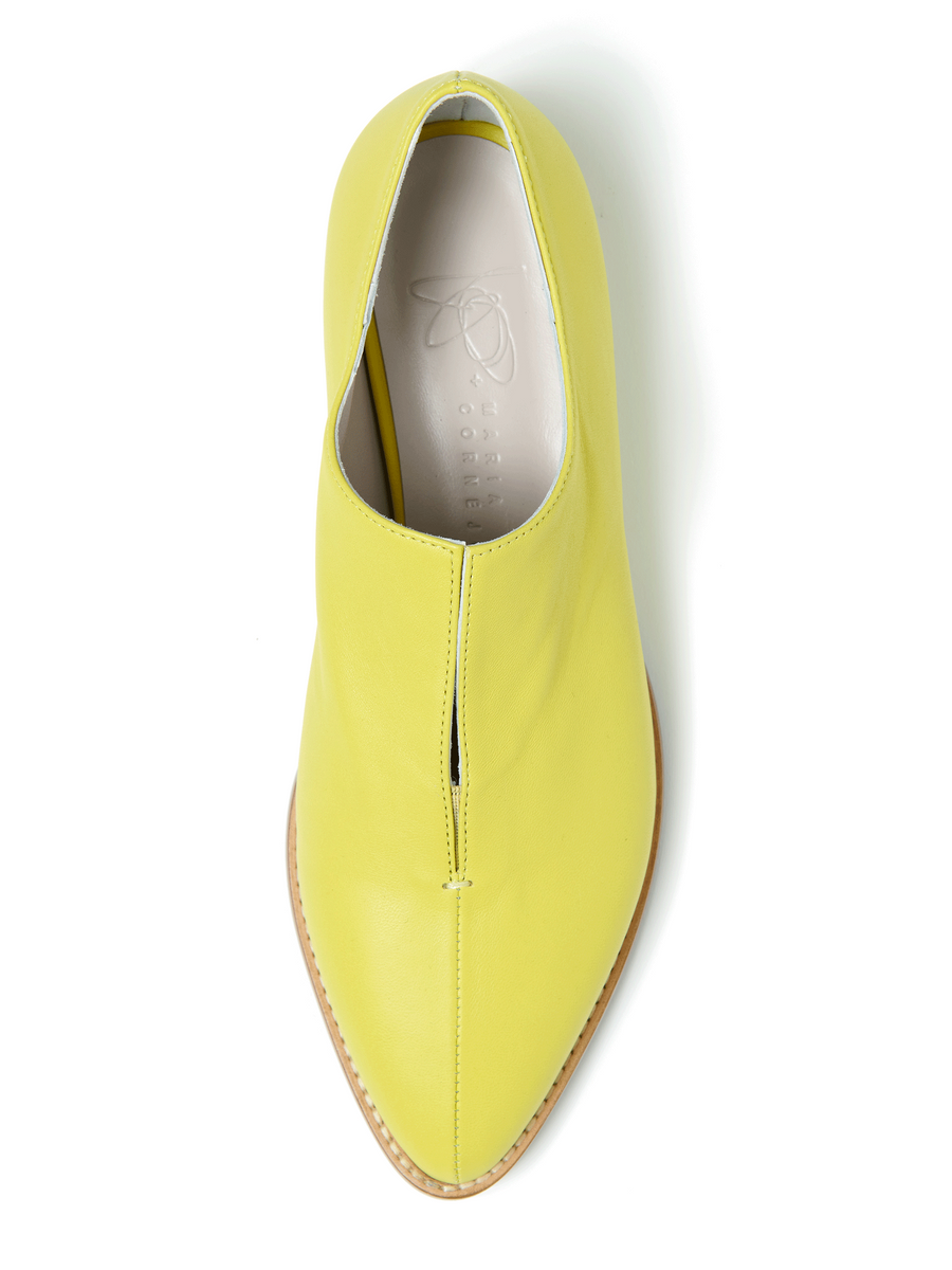 A top view of the Kiara Oxford by Zero + Maria Cornejo features a bright yellow Nappa leather design with a pointed toe, tan sole, and unique slit. The pale insole has embossed branding, offering an elegant fit with Italian sizing.