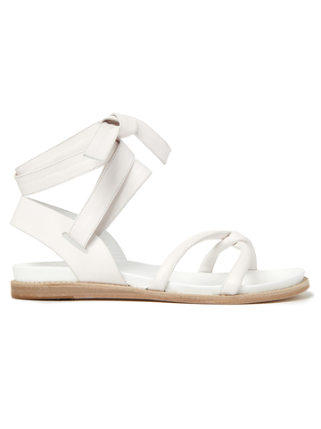 The Limi Sandal by Zero + Maria Cornejo offers a side view of Italian-sized white sandals with ankle straps and flat soles. Made from nappa leather, they have a toe loop, knotted design on the upper, and a light brown sole contrasting with the white straps. Note: Final Sale item.