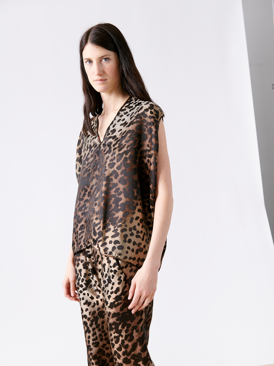 With long dark hair, a person wears the FSC-certified viscose Ina Tank by Zero + Maria Cornejo, styled with matching leopard print pants, and stands against a plain white background, looking directly at the camera.