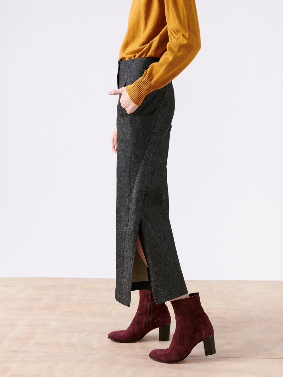 Side view of a person wearing a mustard yellow sweater, the Cropped Fin Pant - Final Sale by Zero + Maria Cornejo, and burgundy ankle boots. They stand on a wooden floor against a plain white background, embodying the innovation of Archroma’s EarthColors® technology in fashion.