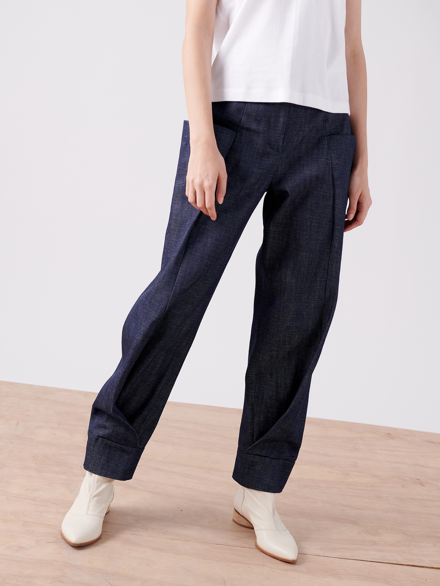 The cropped photo shows a person on a wooden floor wearing a white T-shirt, dark blue organic denim wide-leg pants, and the 