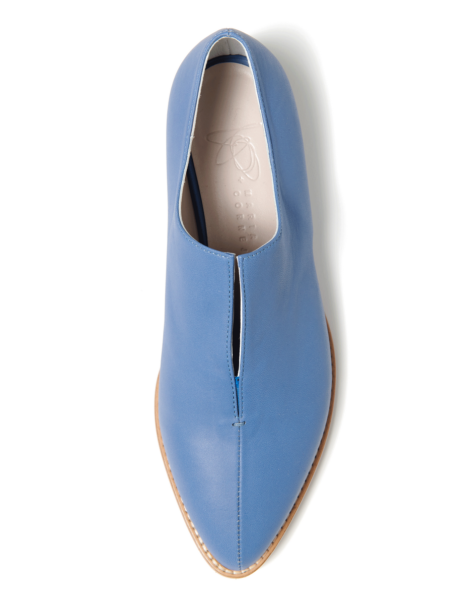 The Kiara Oxford by Zero + Maria Cornejo, a sleek blue slip-on, features Italian sizing and a center cut with a tan sole. Subtle elegance is added by faint interior branding and minimalistic design.